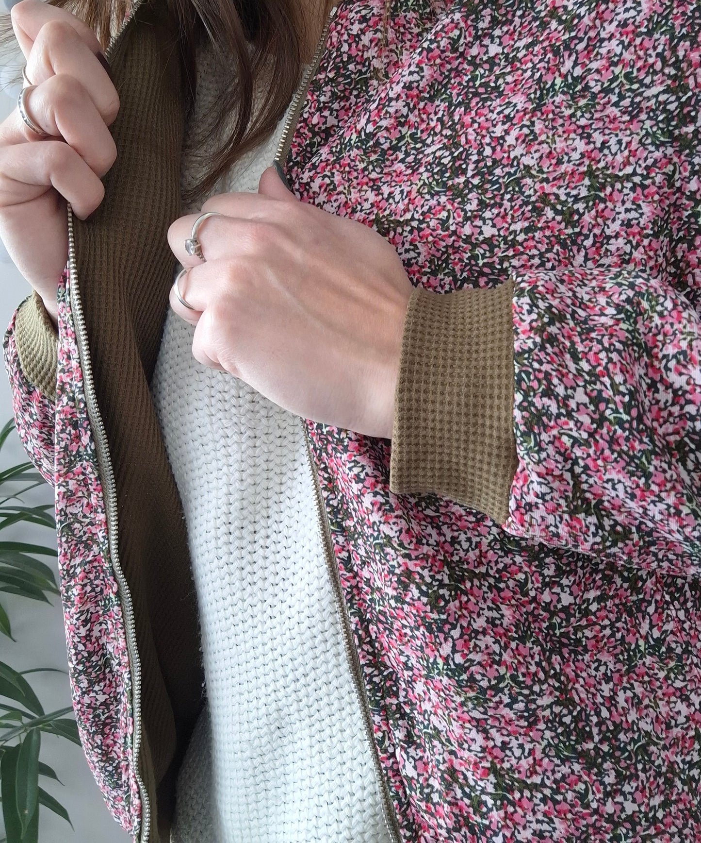 Woman wearing a floral Laura Jo raincoat over a white knit sweater, Le Petit Placard