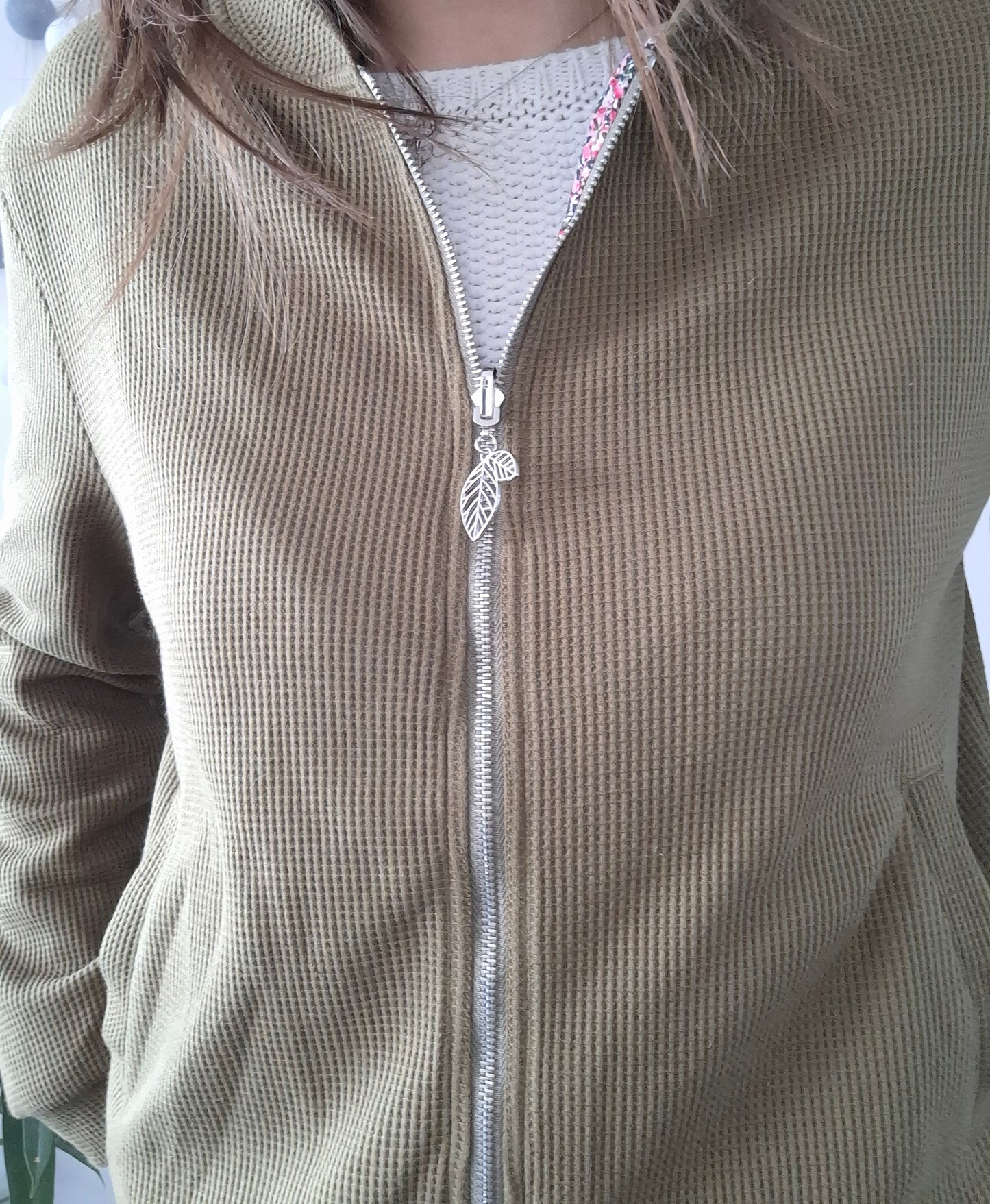 Close-up of a khaki zippered jacket with leaf zipper pull from Le Petit Placard