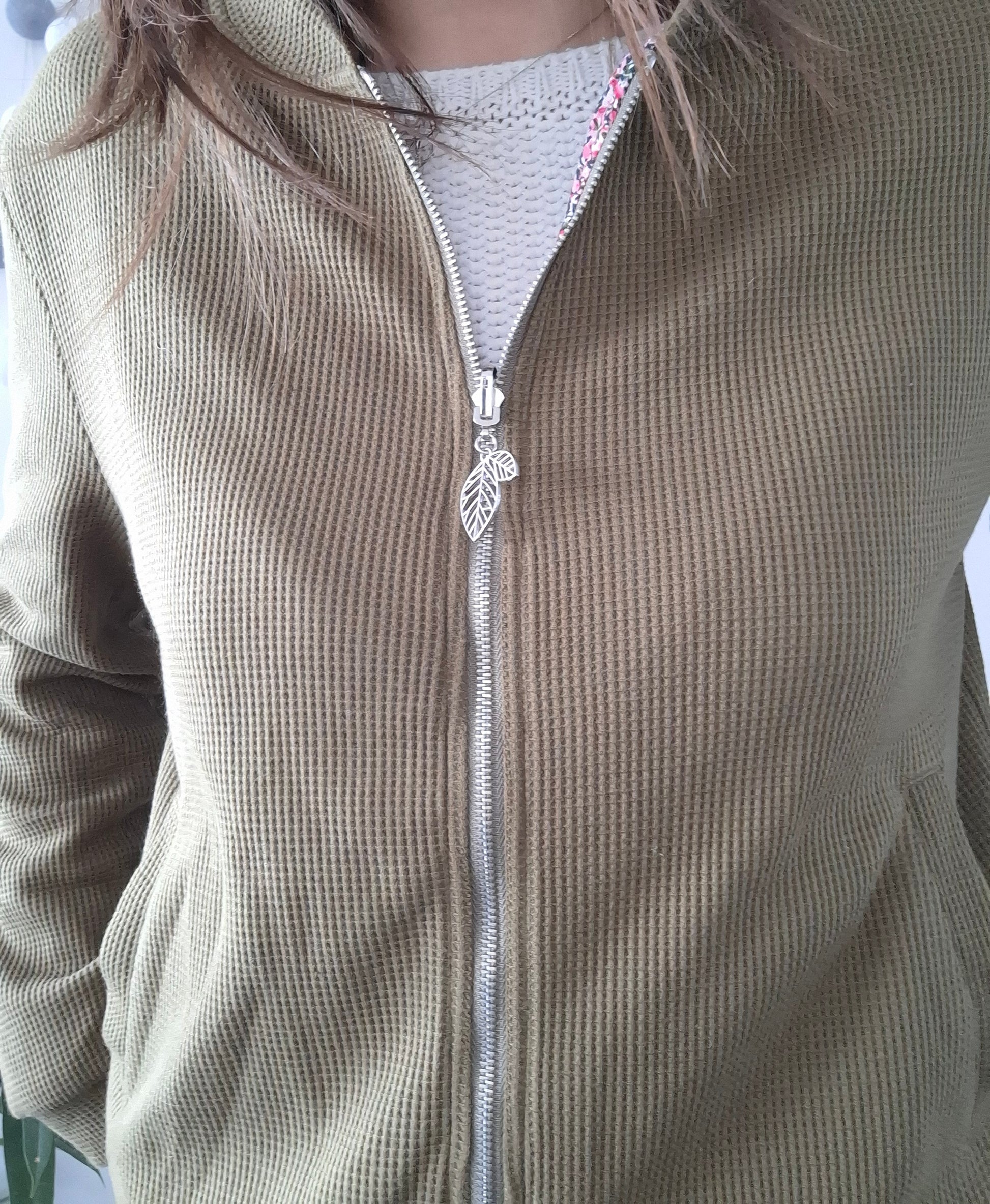 Close-up of a khaki zippered jacket with leaf zipper pull from Le Petit Placard
