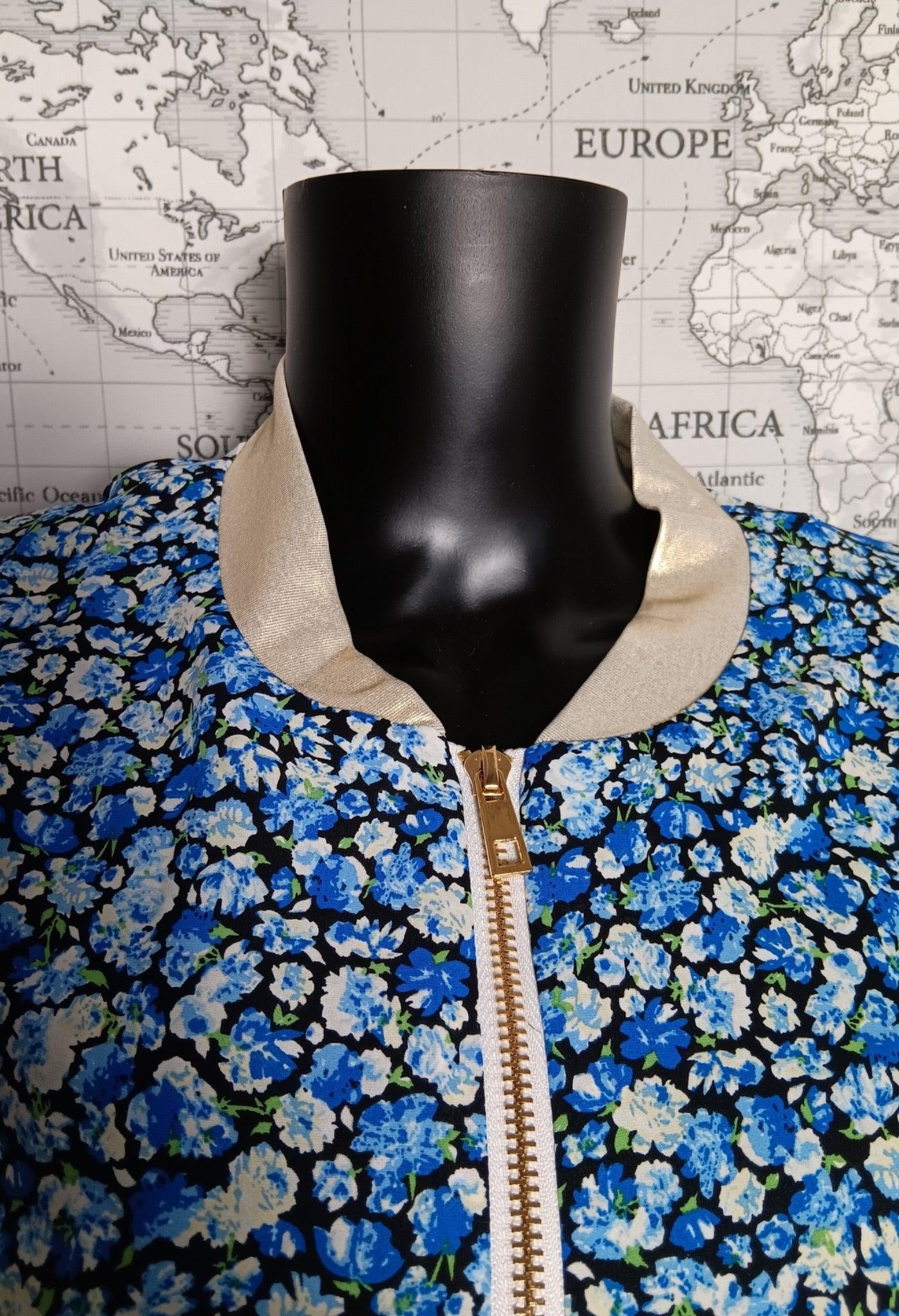 Bomber fleuri femme bleu et blanc, col beige et fermeture éclair dorée, affiché sur mannequin.