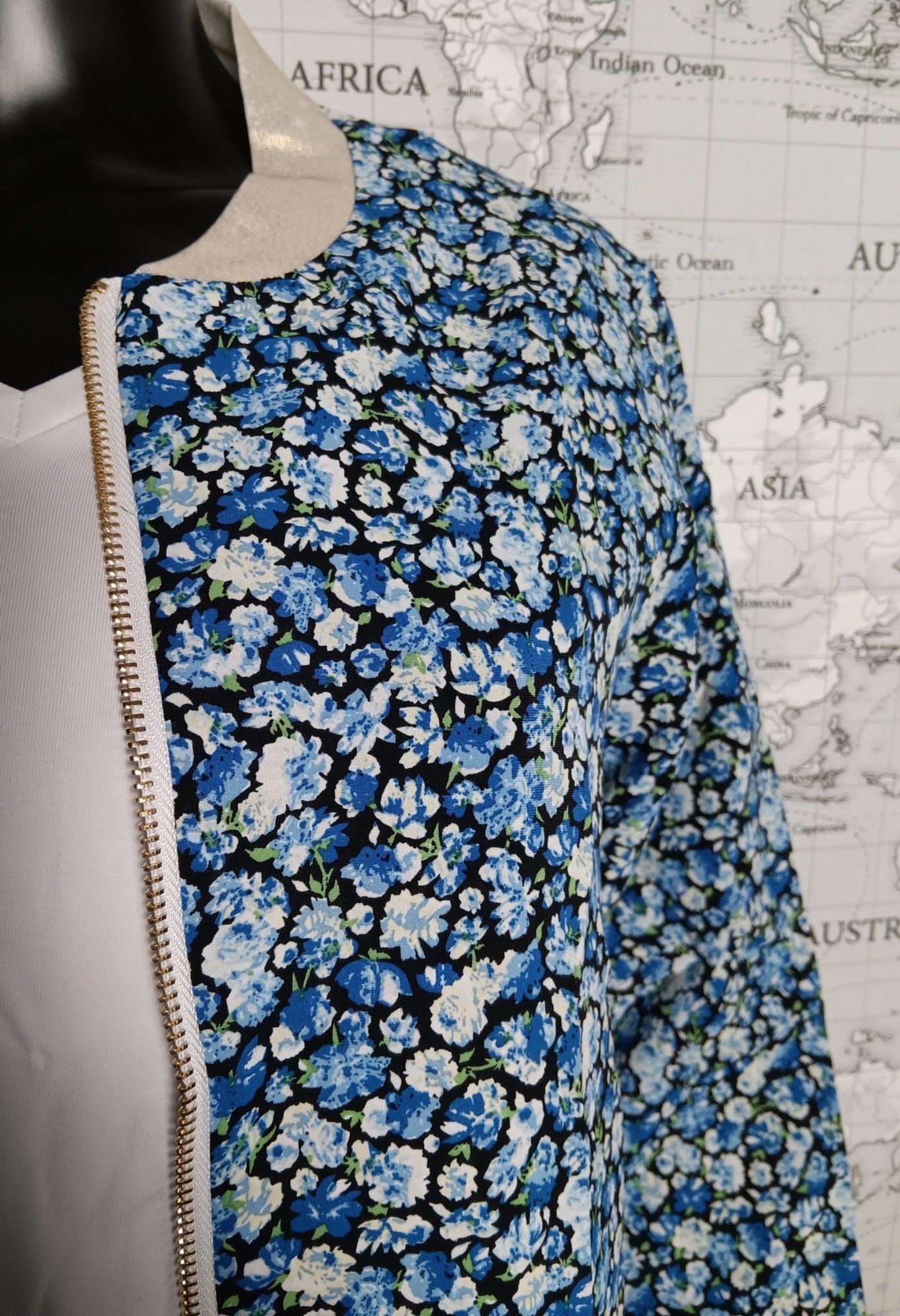 Bomber fleuri femme tones bleus: motif floral petit blooms sur fond noir, fermeture dorée latérale, porté sur mannequin.
