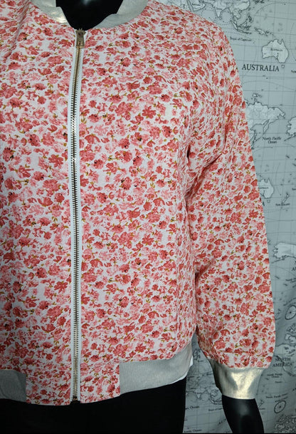 Veste légère femme à motifs floraux rouges et orangés, fermeture zippée sur le devant, bord-côtes gris à la base et poignets argentés.