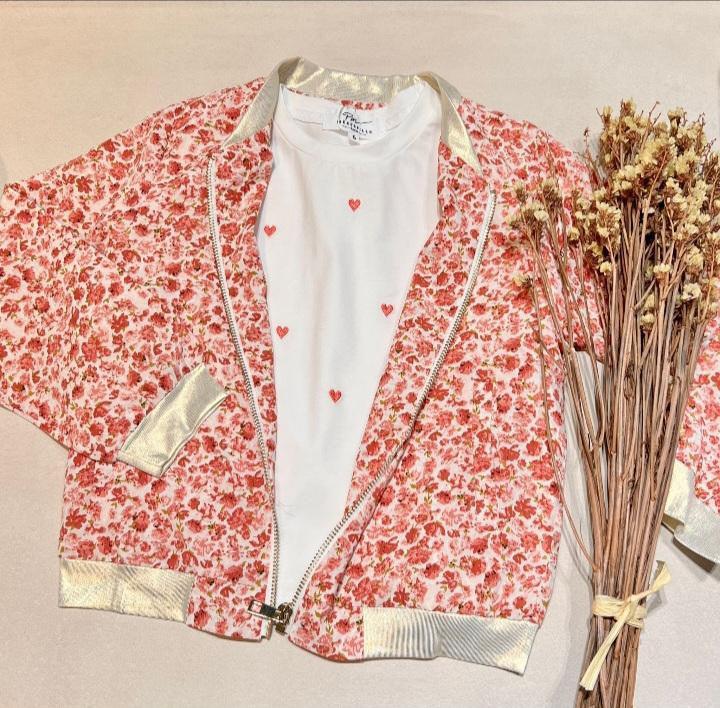 Veste légère fleurie rouge-orangé pour femme, bomber romantique avec intérieur blanc à petits cœurs rouges, bordures dorées et zip visible.