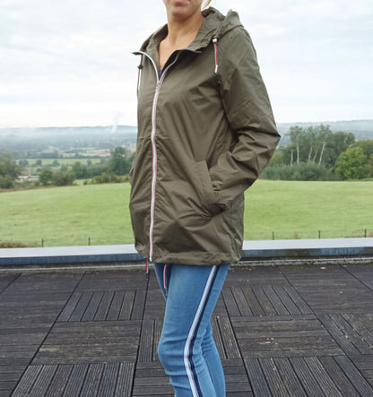 Femme en imperméable kaki Laura Jo et jean à rayures bleues sur une terrasse en bois, vue sur la campagne
