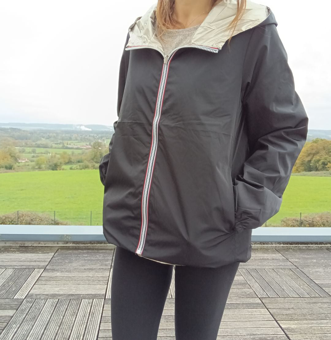 Manteau court réversible imperméable noir et doré Melya Melody porté par une femme, côté noir avec zip rouge visible