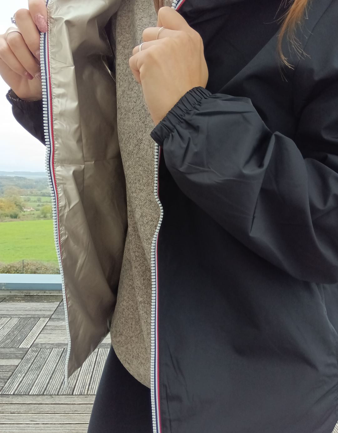 Détail réversible du manteau court imperméable noir et doré Melya Melody, avec fermeture éclair bicolore visible