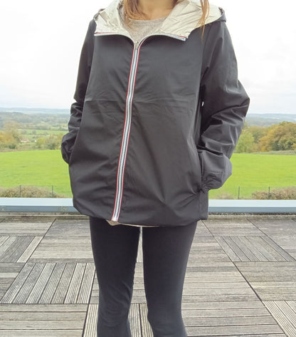 Manteau court réversible imperméable noir porté côté noir, avec capuche dorée visible et fermeture éclair bicolore – Melya Melody