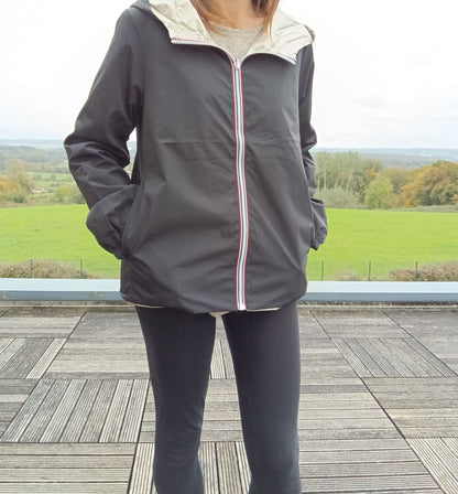 Manteau court réversible imperméable noir porté côté sombre, zip tricolore, capuche dorée visible, Melya Melody