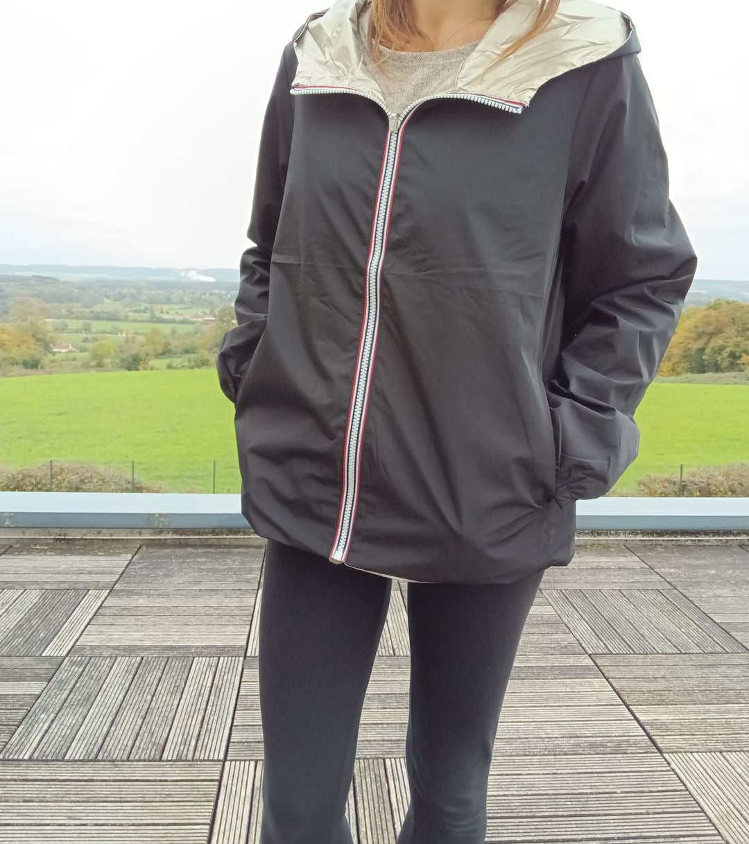 Manteau court réversible imperméable noir et doré Melya Melody porté par une femme, côté noir visible