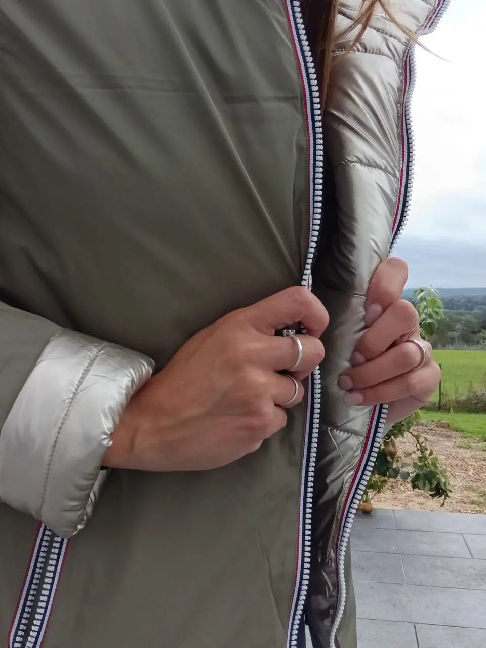 Manteau réversible imperméable Melya Melody femme kaki et doré, avec capuche et fermeture à boutons, porté sur un fond neutre.