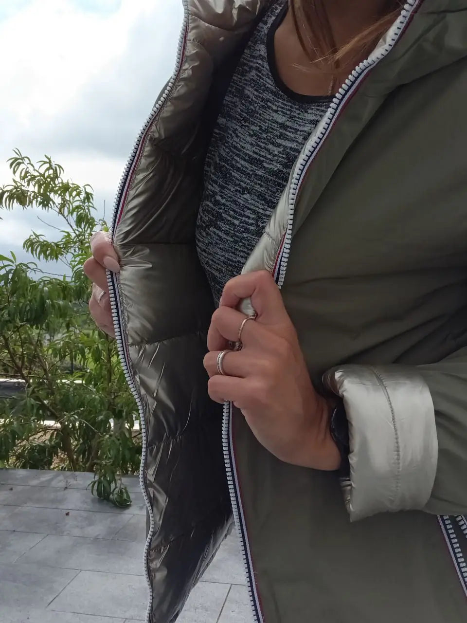 Manteau réversible imperméable Melya Melody pour femme, côté kaki avec détails dorés, porté en plein air.