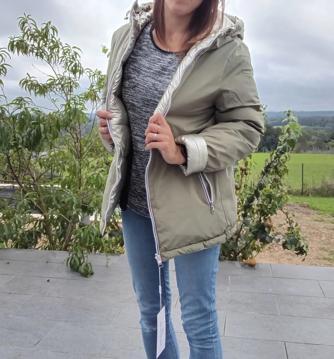 Manteau réversible imperméable Melya Melody femme kaki et doré, avec capuche et poches, porté en extérieur.