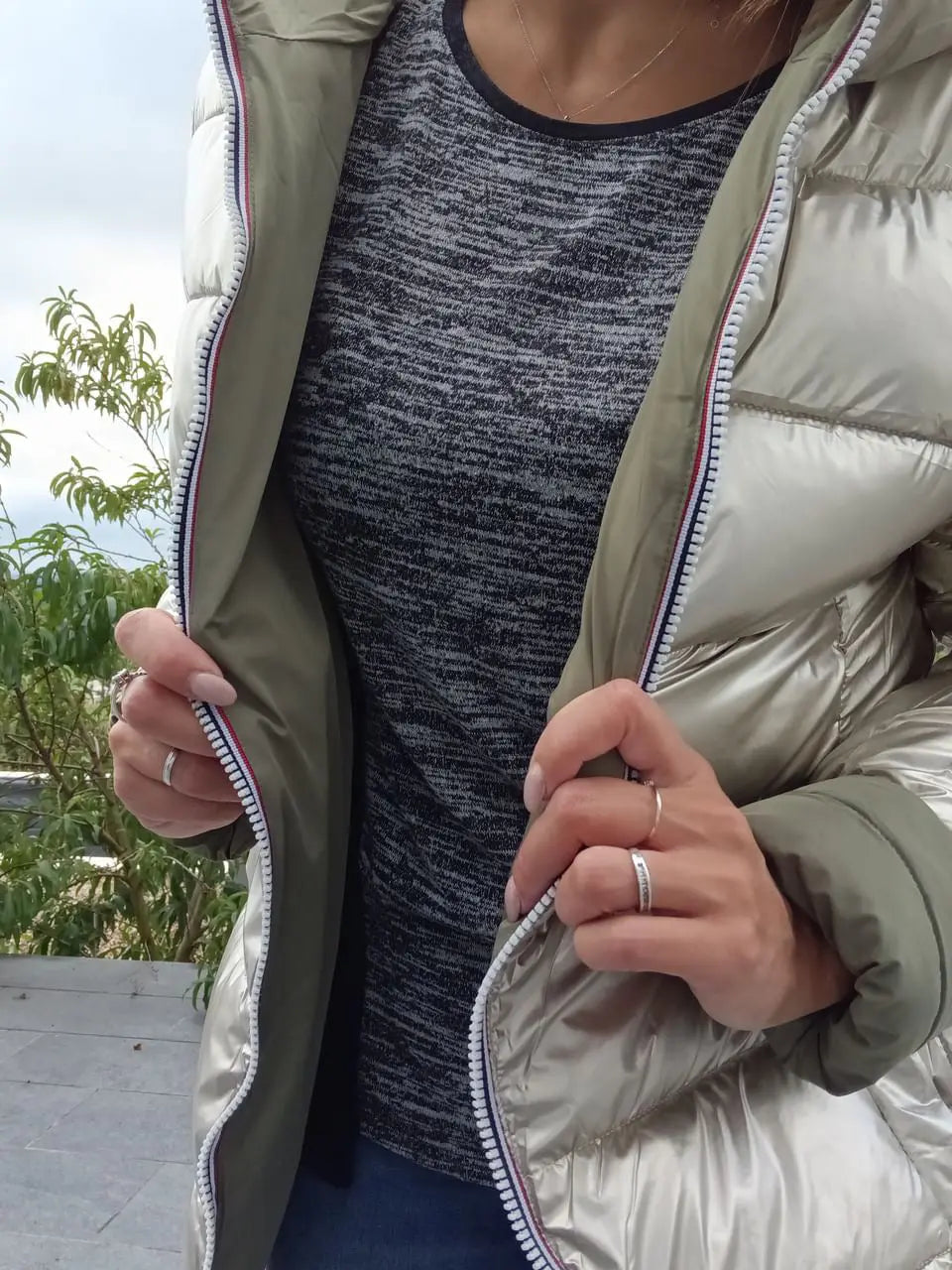 Manteau réversible imperméable Melya Melody pour femme, kaki et doré, avec capuche et poches, porté en extérieur.