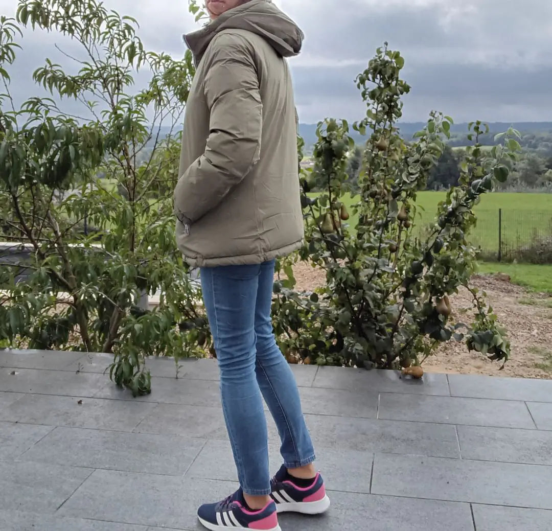 Manteau réversible imperméable Melya Melody femme kaki et doré, porté, avec capuche et fermeture éclair visible.