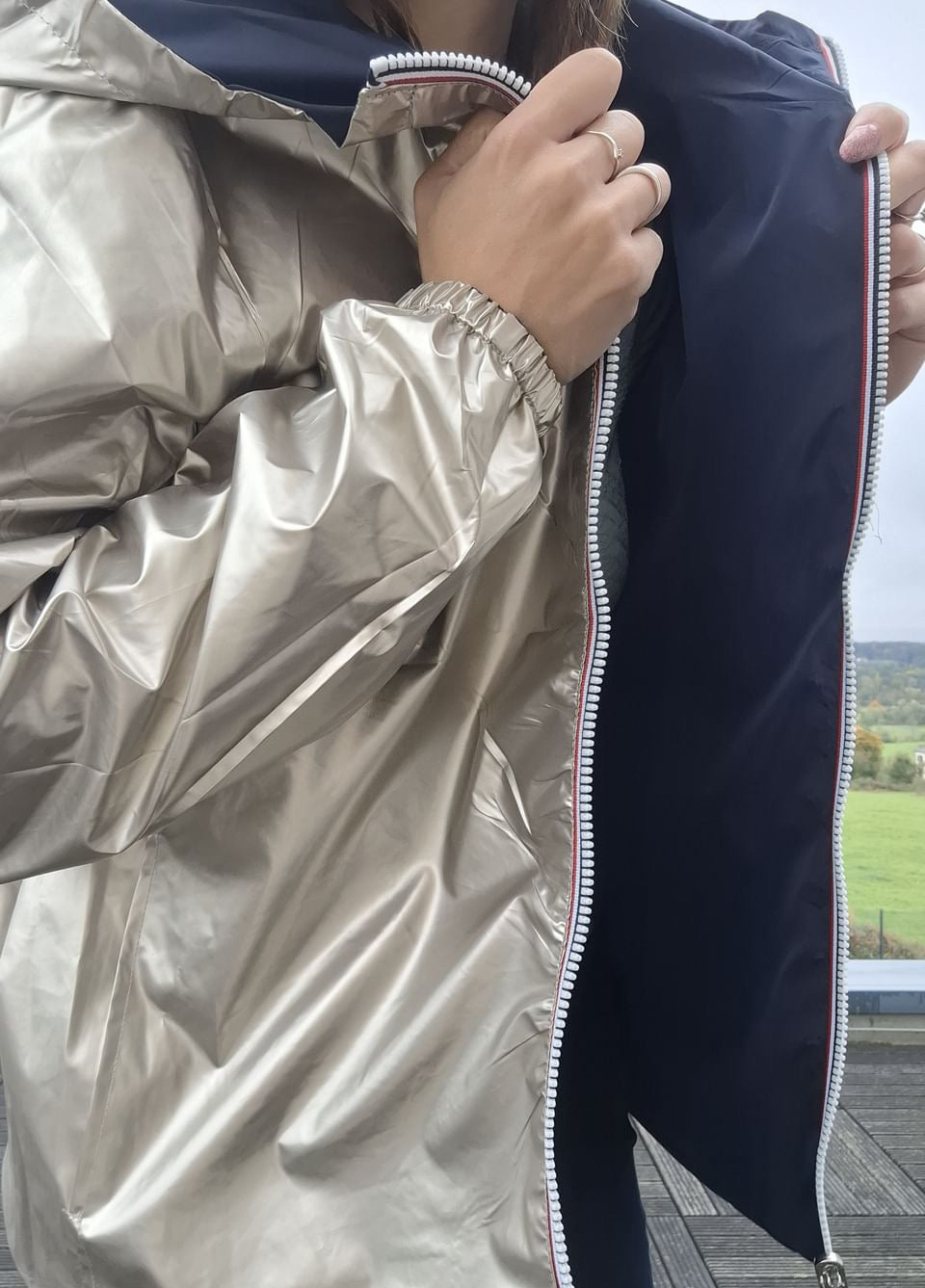 Détail du manteau court imperméable réversible Melya Melody, côté doré métallisé et côté bleu marine avec fermeture éclair bicolore