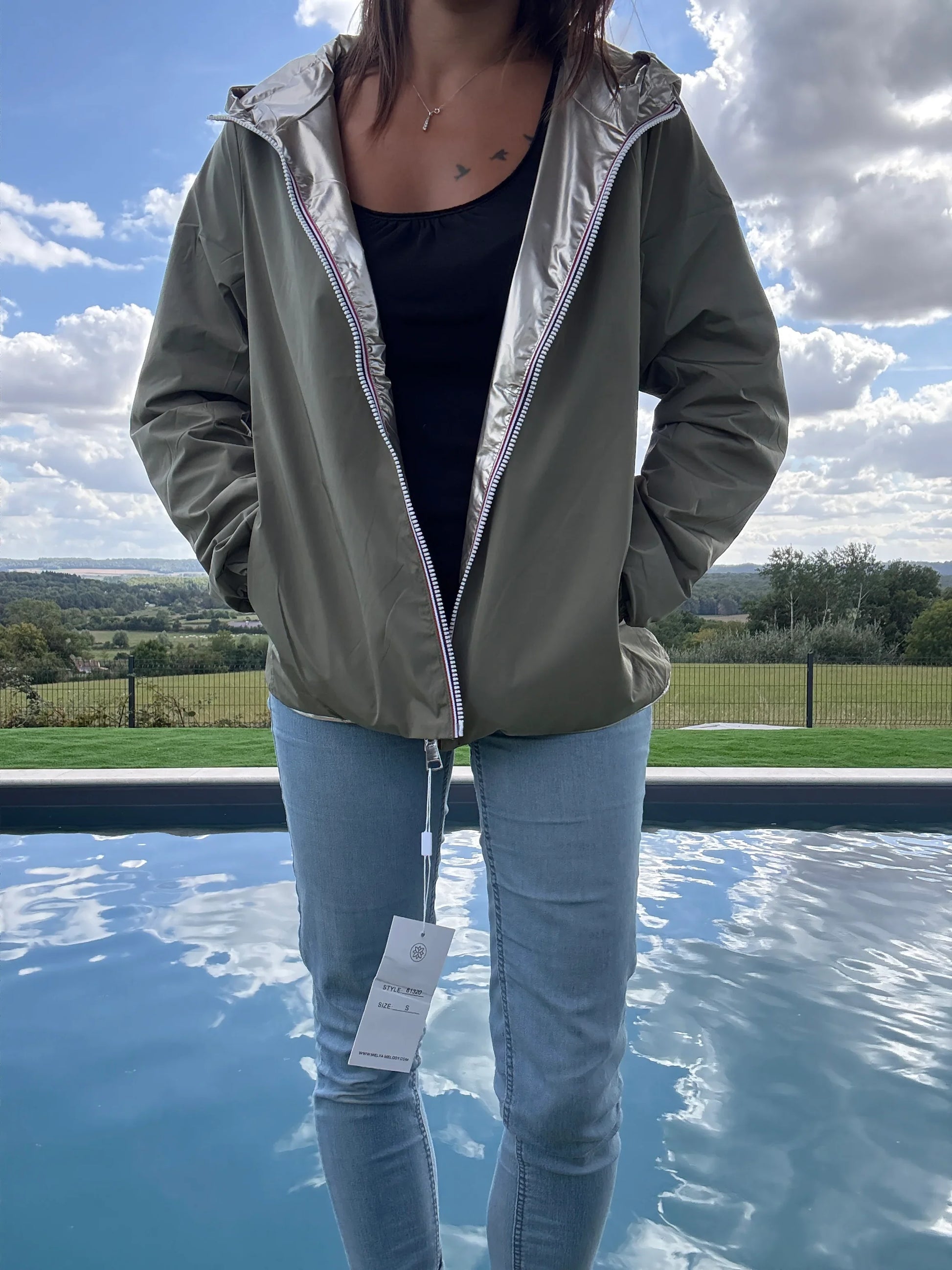 Manteau court imperméable kaki réversible doré Melya Melody porté ouvert sur jean, au bord d'une piscine