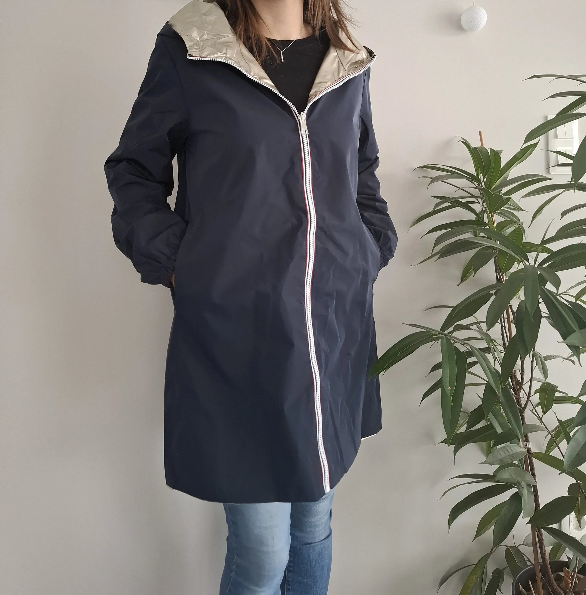 Woman wearing Laura Jo navy raincoat with silver hood, hands in pockets, Le Petit Placard