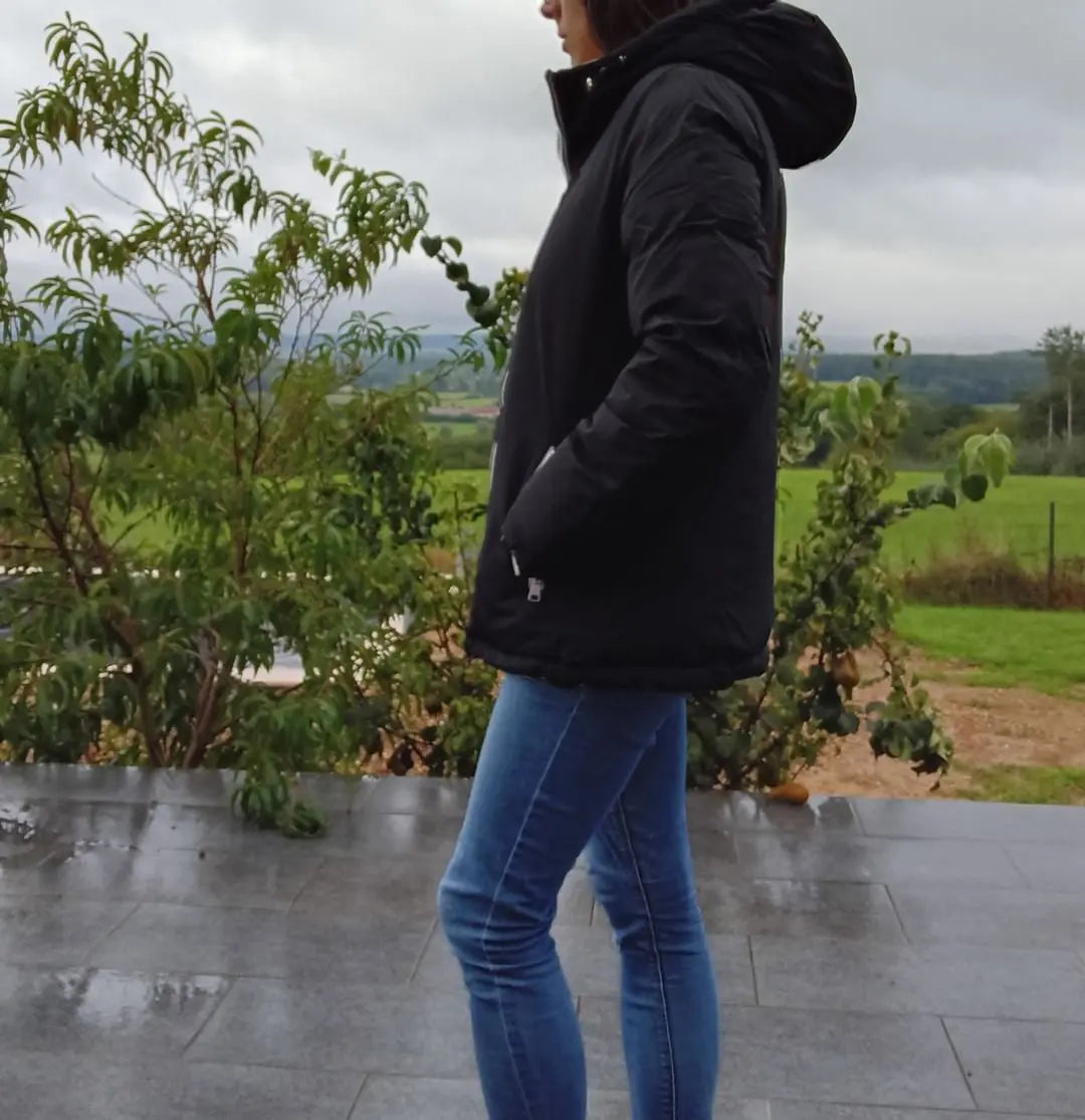 Manteau court réversible et imperméable Melya Melody noir et doré, matelassé, avec capuche et fermeture éclair.