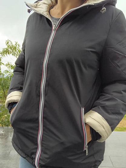 Manteau court réversible Melya Melody, imperméable et matelassé noir et doré, porté avec capuche et fermeture éclair visible.