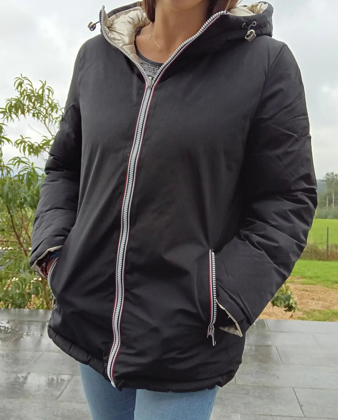 Manteau court réversible noir et doré de Melya Melody, imperméable et matelassé, porté en extérieur, vue de face.