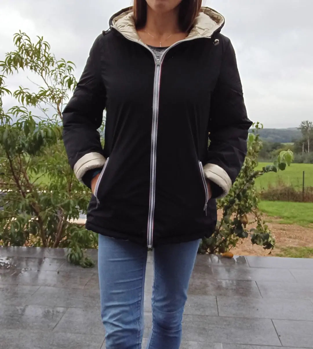 Manteau court réversible et imperméable Melya Melody, matelassé noir et doré, porté en extérieur.