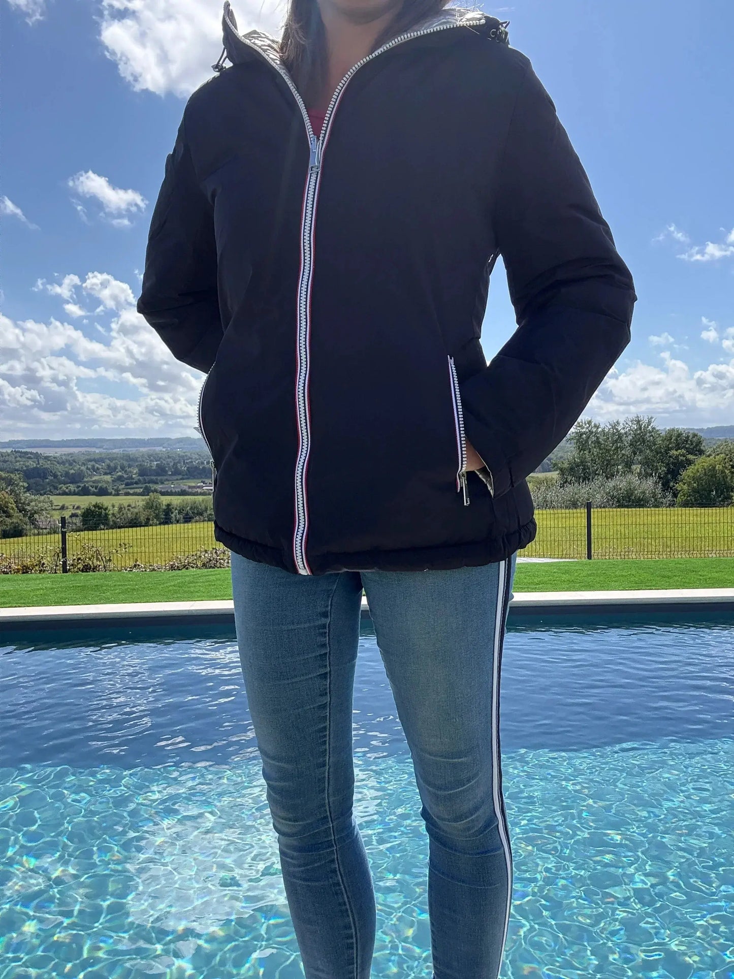Manteau court réversible et imperméable Melya Melody, matelassé noir et doré, porté avec capuche et fermeture éclair.