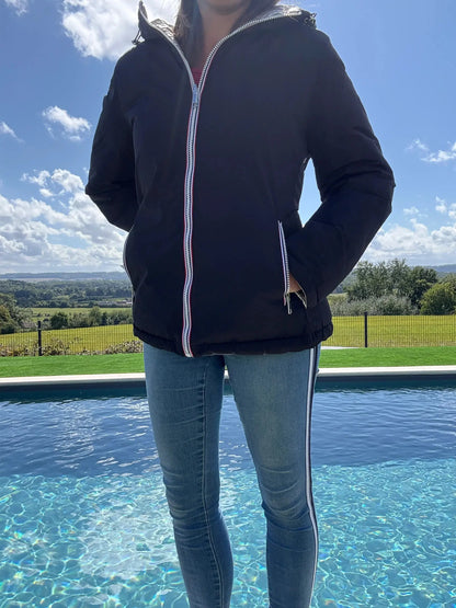 Manteau court réversible et imperméable Melya Melody, matelassé noir et doré, porté avec capuche et fermeture éclair.