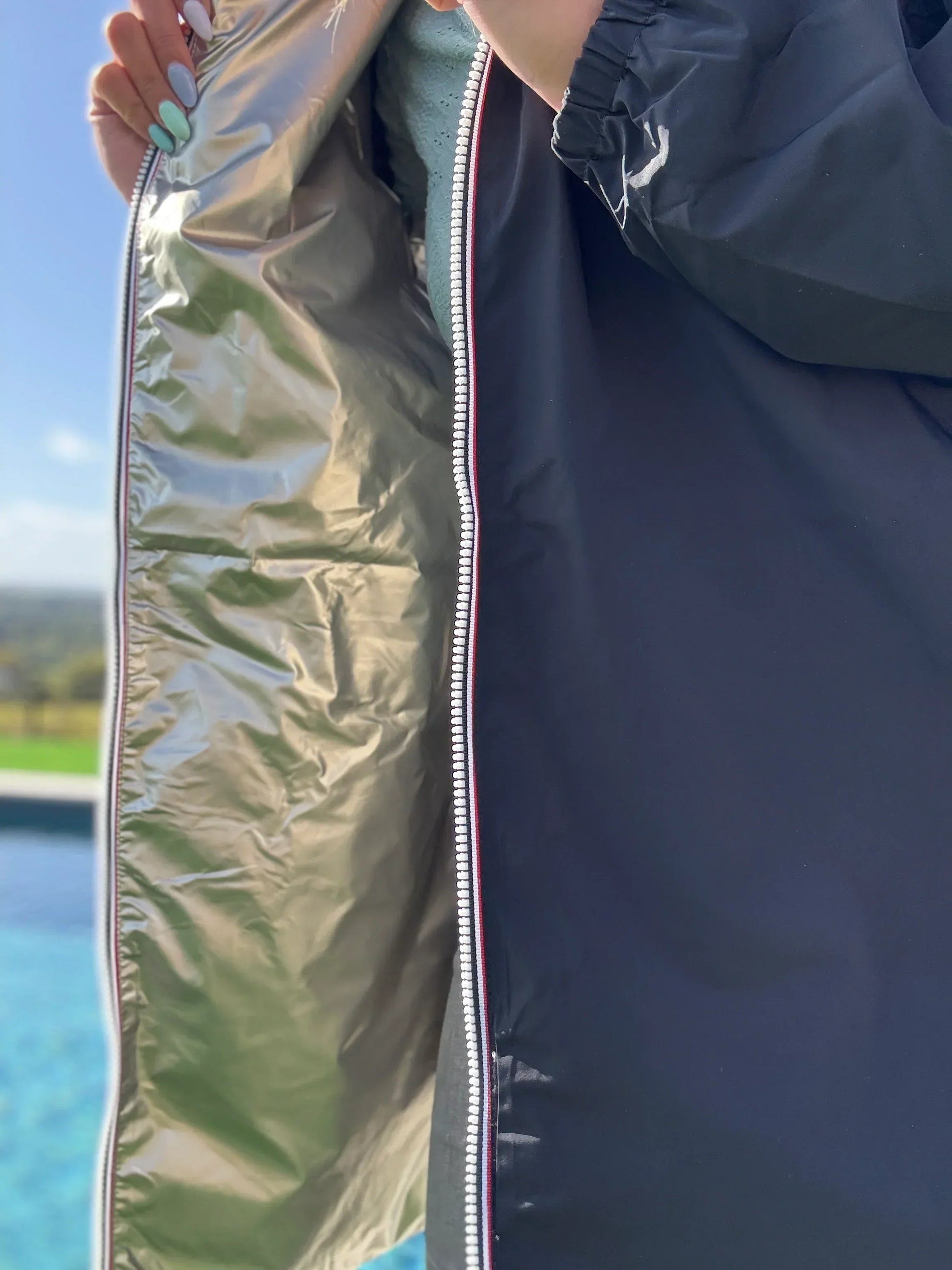 Manteau léger long réversible imperméable noir et doré de la marque Melya Melody, avec capuche et fermeture éclair visible.